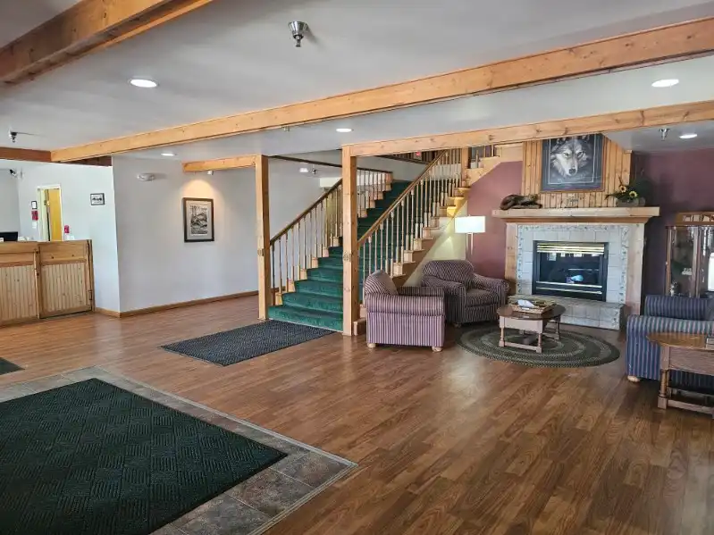The lobby, with a fireplace, armchairs and the open staircase to the upper floor