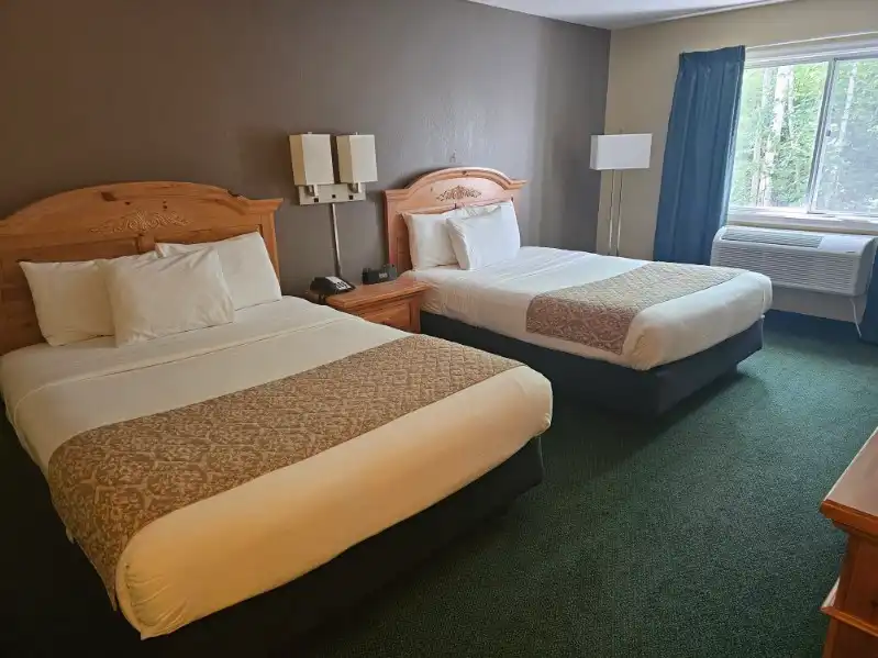 A guest room at Country Inn of Hoyt Lakes with two beds and a window onto the trees