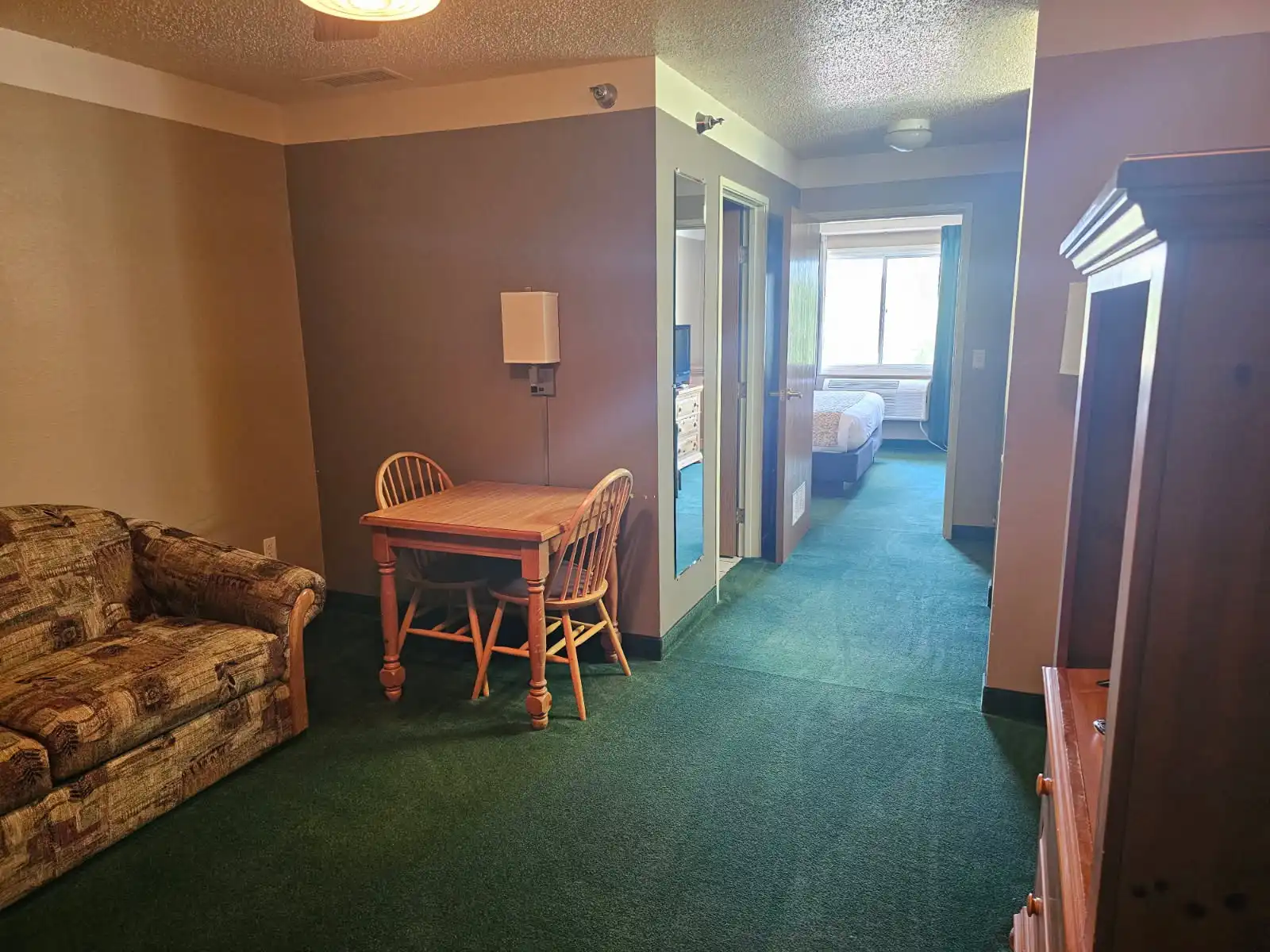 A suite living area with a sofa, a dining table and the bedroom beyond