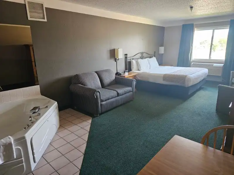 A guest room with a corner whirlpool tub and a king bed